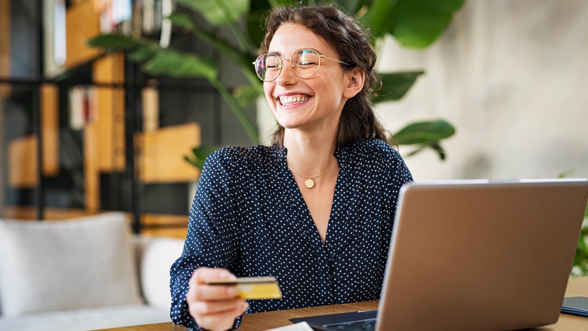 Millennial woman with a debit card at a laptop 